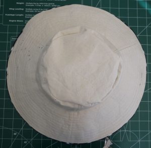 Top view finished sun hat( cream side with blue piping) on a green background