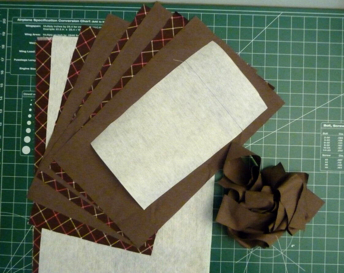 Brown fabric, white stabilizer and brown binding strips on a green background