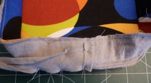 Close up of grey bias tape with a folded over edge pinned to Side Panel Interior (Igrey)