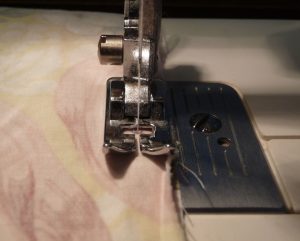 Closeup of sewing machiine presser foot sewing 1/4" seam allowance