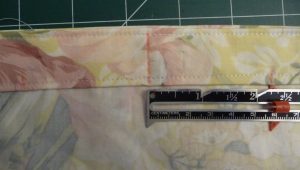 Seam gauge showing marks at centre and 2.25" from center on floral fabric