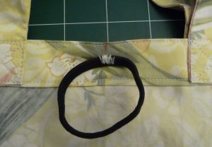 Black hair elastic sewn midway between handles on bag interior