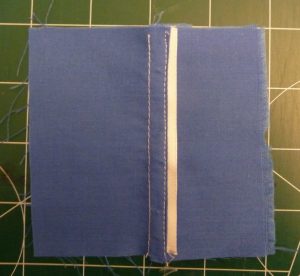 White thread and white ribbon used to sew a decorative flat felled seam in blue fabric