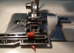 Close up of a sewing machine with an adjustable guide presser foot set to 1/2"