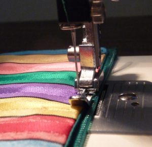 Close-up of a zipper being sewn onto a zipper pouch with vertical stripes