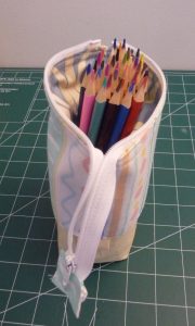 Side view of standing slide pen pouch with top lowered to reveal 36 colored pencils